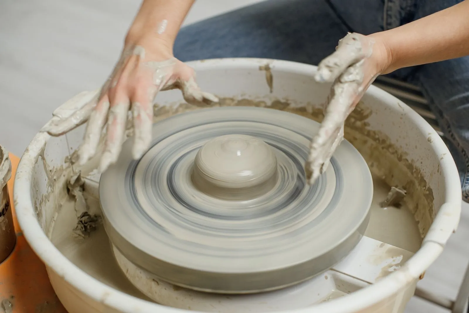 Close-up of hands sculpting clay on a pottery wheel, showcasing craftsmanship.